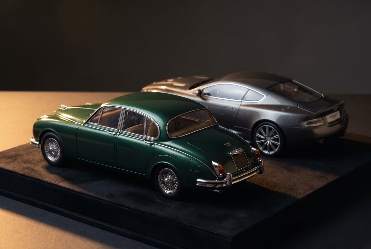 Two premium 1:18 scale collector model cars from different manufacturers, viewed three-quarter rear on a dark surface
